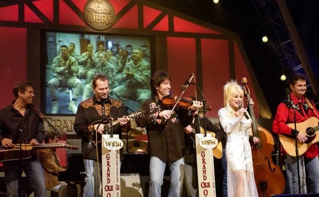 November 28. Country star Dolly Parton sings on stage during a Grand Ole Opry live broadcast in Nashville, Tenn., April 23 as U.S. soldiers watch the show via a video feed in Iraq. Credit US Department of Defense
