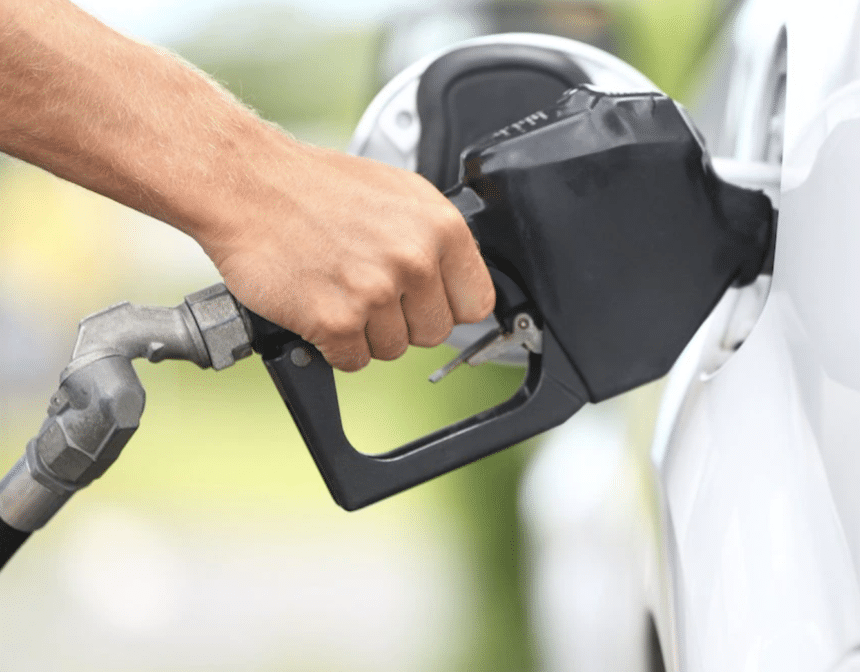 A hand on a gas pump filling a vehicle