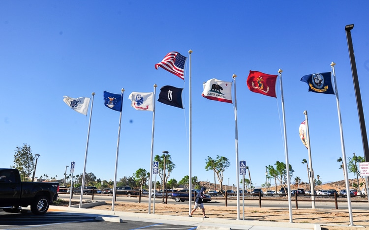 A student bends and braces while striding into blustery headwinds that are whipping flags Wednesday on the Norco College campus.