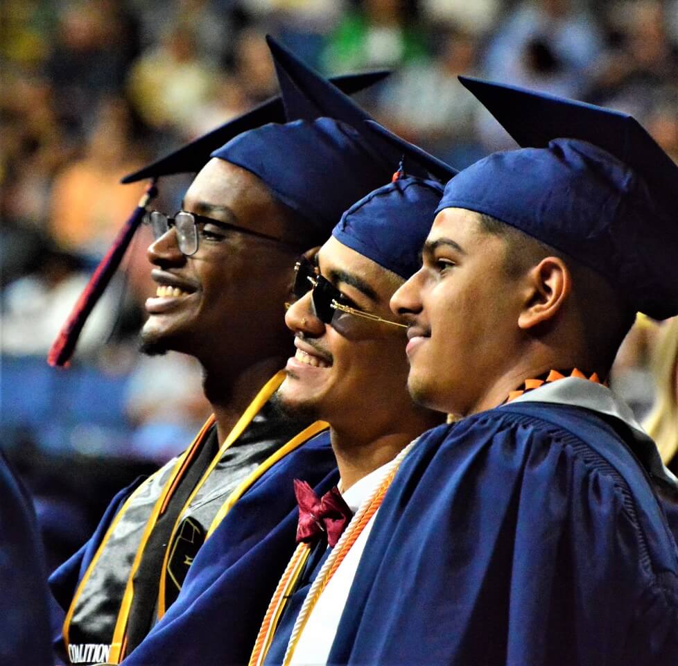 Ty Stuart (left), Tony Smith (middle) beam while they wait to receive their diplomas.