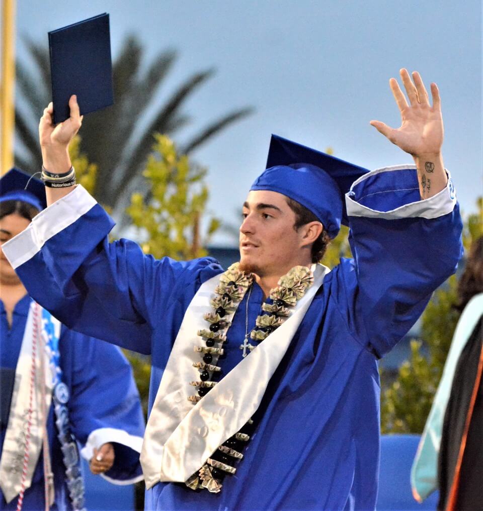 Norco High Baseball player Justin Mondini signals to family and friends after receiving his diploma. 
