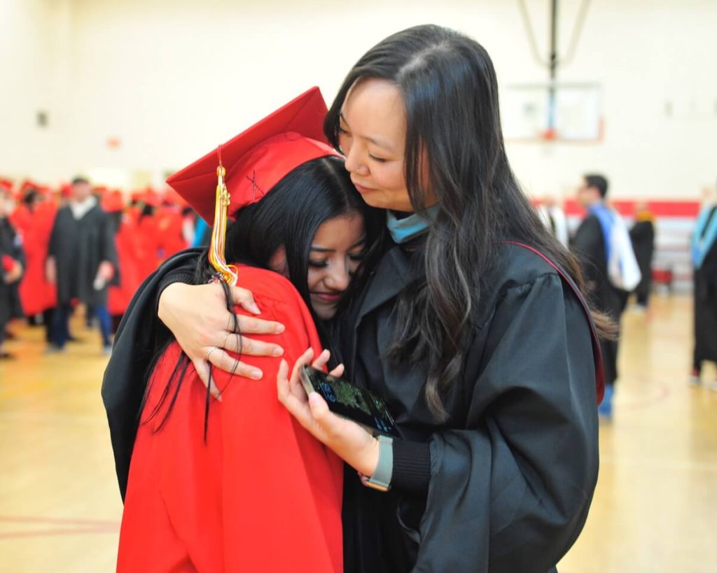 Local schools Graduating Corona High honors student Brenda Castro Pineda is hugged by teacher Sharon Chi before the processional at graduation ceremonies.