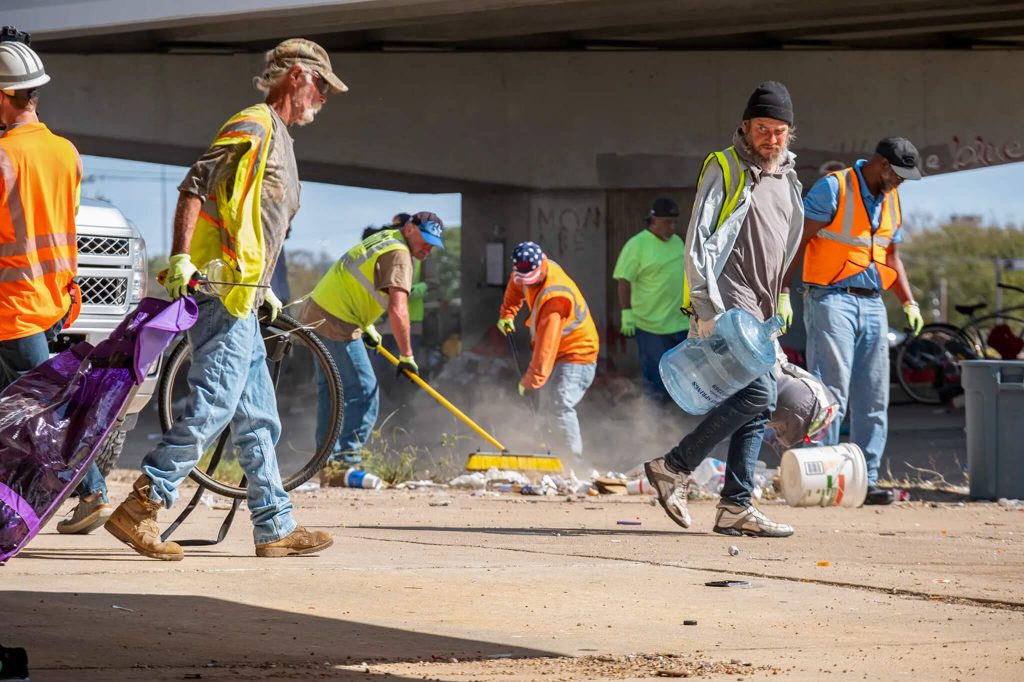 Temporary Workers, contracted by the Texas Department of Transportation, remove trash and personal belongings from a homeless encampment under U.S. Route 290 at Westgate Boulevard in Austin, Texas on Nov. 4, 2019. Photo By Jordan Vonderhaar