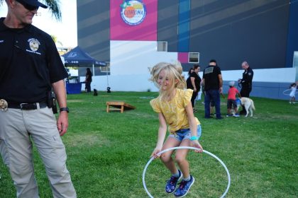 Haley Siemer, the daughter of Corona Police Cp. Russell Siemer, jumps through a hula-hoop as her father watches at National Night Out in 2022. This year’s Night Out with Corona PD takes place this coming Tuesday.