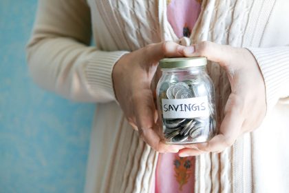 Saving For Retirement. Woman holding a jar full of coins with a tag reading savings. Photo by Towfiqu barbhuiya on Unsplash