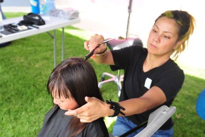 Genesis Bahema, 3, of Corona, gets a haircut from Leilani Hunter, of Corona, during the Leela Project Barbers & Backpacks event at the Circle City Center in Corona last Saturday. More photos on Page 8 Credit: Photo by Jerry Soifer