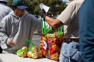 Volunteer Kim Palma passes out fresh produce at the Solano County Mobile Food Pharmacy in Fairfield. Photo by Semantha Norris, CalMatters