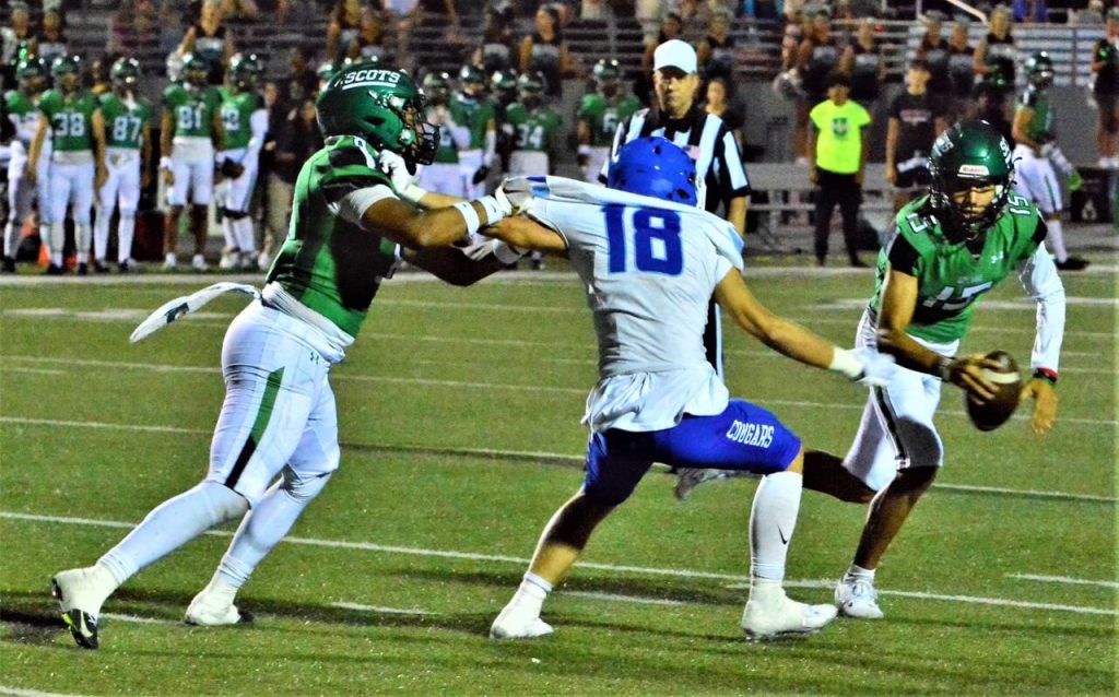 Upland running back Donovan Brown (left) has a hold of Norco defender Randy McDaniel (18) stopping him from getting to quarterback Noah Sandoval (15) during the Scots 44 – 7 rout of the Cougars last Friday night.  Norco was called for defensive holding on the play.
Credit: Photo by Gary Evans
