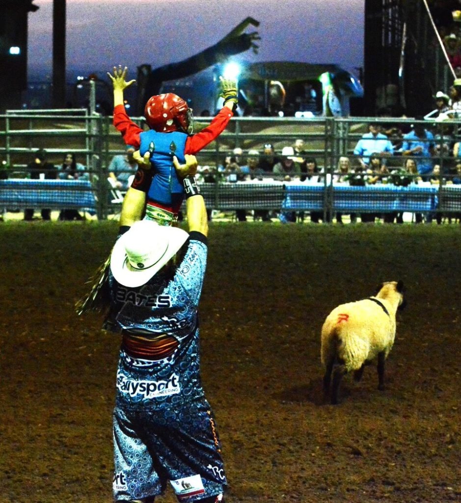 A rodeo clown holds Ryder Hallam aloft after Hallam’s successful ride in mutton busting Sunday night at the Norco Fair. 
Credit: Photo by Gary Evans
