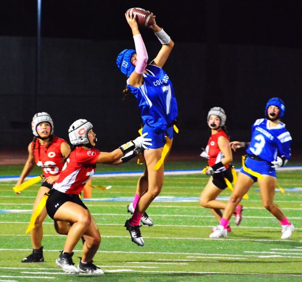 Corona defender Fia Liaga (left) has hold on Norco receiver Josie Ray (7) flag as Ray catches a pass from QB Mya Arriola (3). The Panthers defeated the Cougars for the first Big VIII Girls Flag Football championship 44 – 19. Credit: Photo by Gary Evans