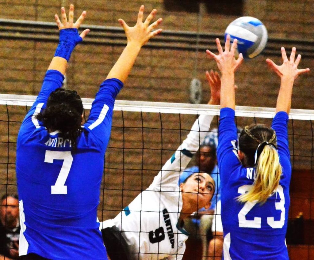 Corona Santiago’s Sarah Guzzetti (9) watches her spike attempt over Norco’s Devyn McCall (7) and Savannah Smith (23) . The Sharks took the first game, but the Cougars won the next three to claim the league championship. Credit: Photo by Gary Evans