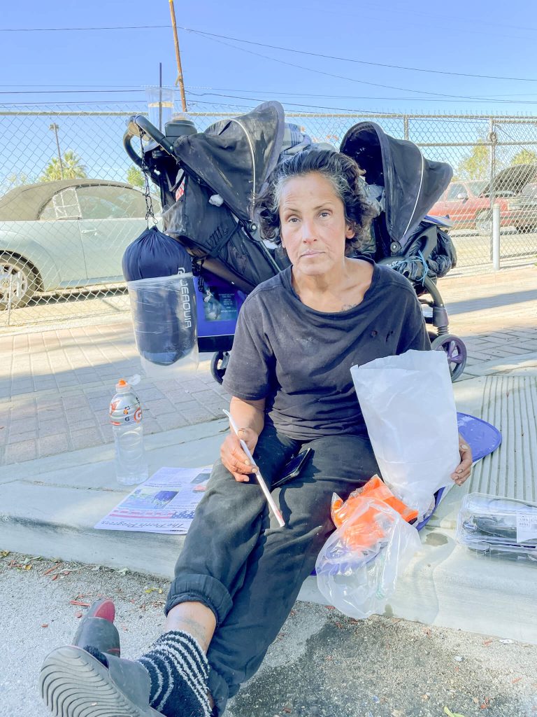 Denise Bustamante graciously accepted a meal from a caring stranger on D Street in Perris. Her new sleeping bag hangs in the background. 
Credit: Photo by Don Ray
