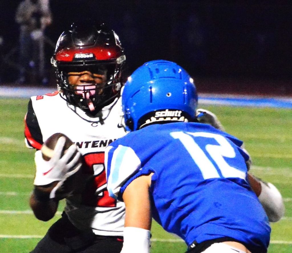 Corona Centennial running back Cornell Hatcher Jr. (2) eyes Norco defender Christian Hernandez (12) during a second quarter drive. Hernandez later intercepted a pass, but the Huskies routed the Cougars 55 – 0 to end the Big West Upper Division season. The league champs host Orange Lutheran in the Division 1 Quarterfinals next Friday, November 10 at 7 pm. Credit: Photo by Gary Evans