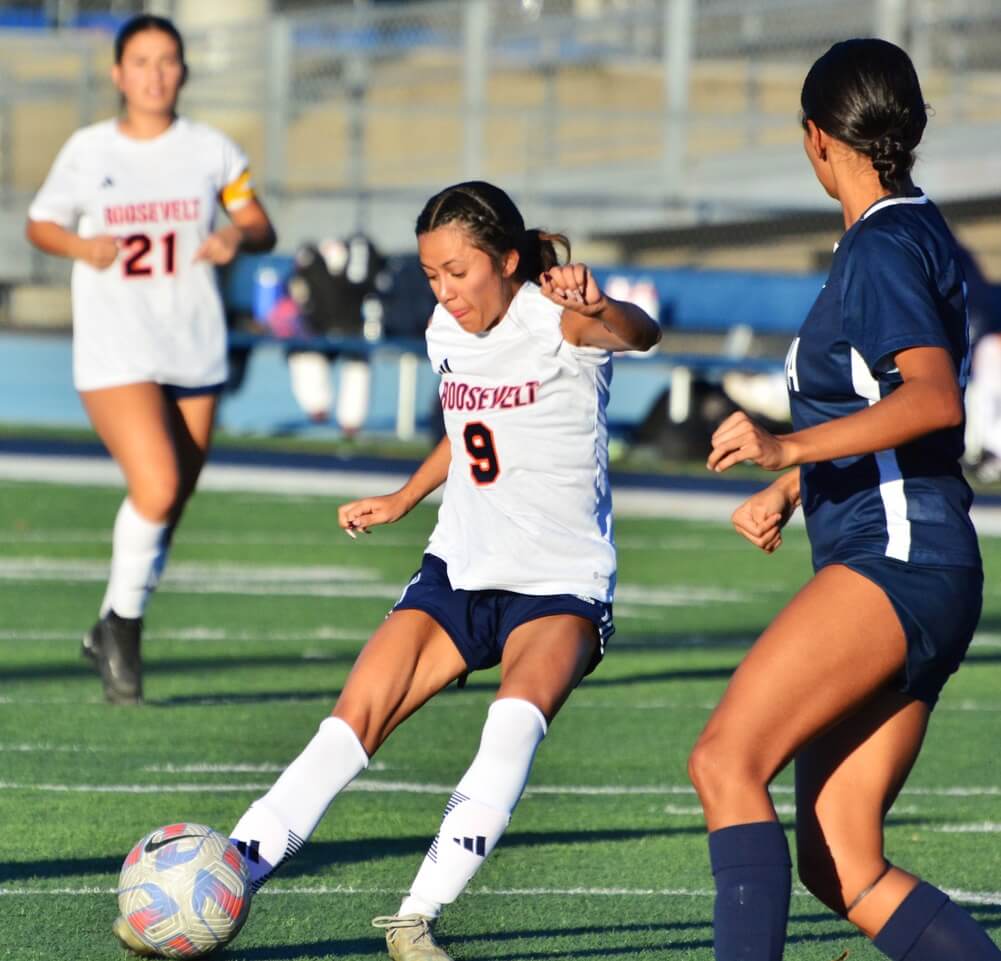 High School Sports Photos and Weekly Scoreboard - 12/08/2023. Eastvale Roosevelt’s Breanna Arredondo (9) launches a shot on goal as Sophia Leoro (21) watches the kick.