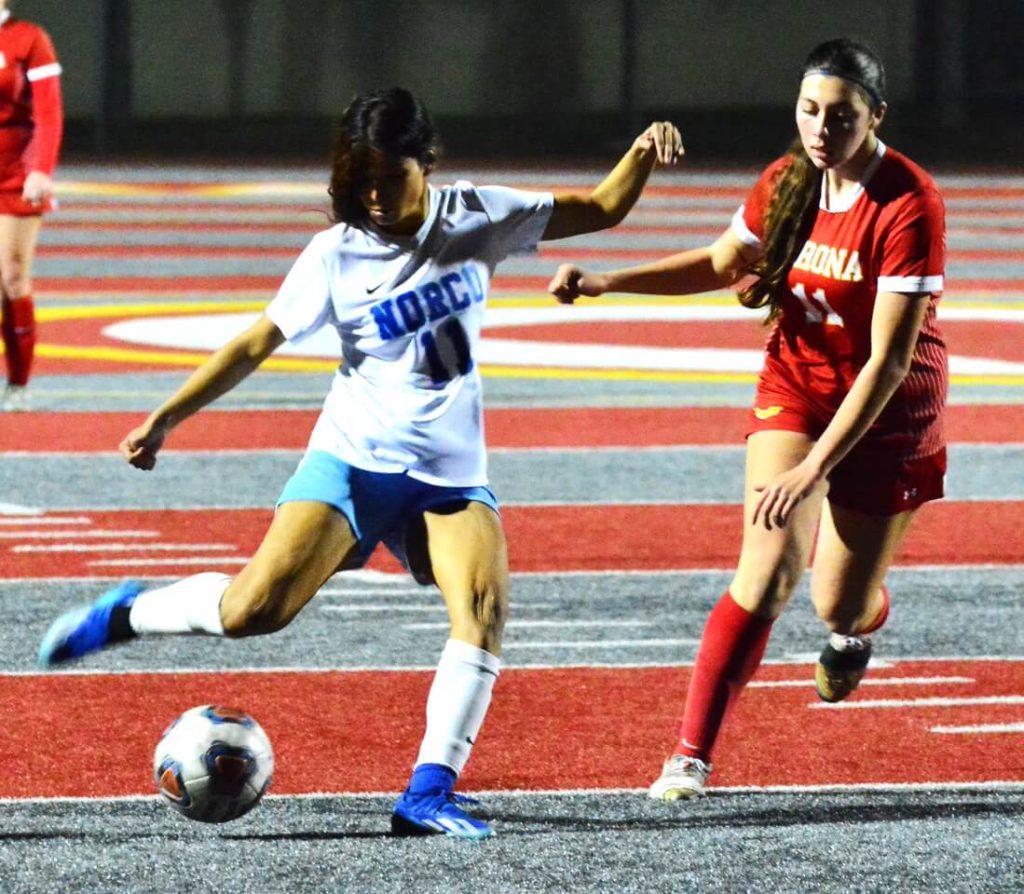 Norco’s Ashlee Bahena (11) takes a shot on goal while Corona’s Vanessa Dias (11) defends. Photo by Gary Evans