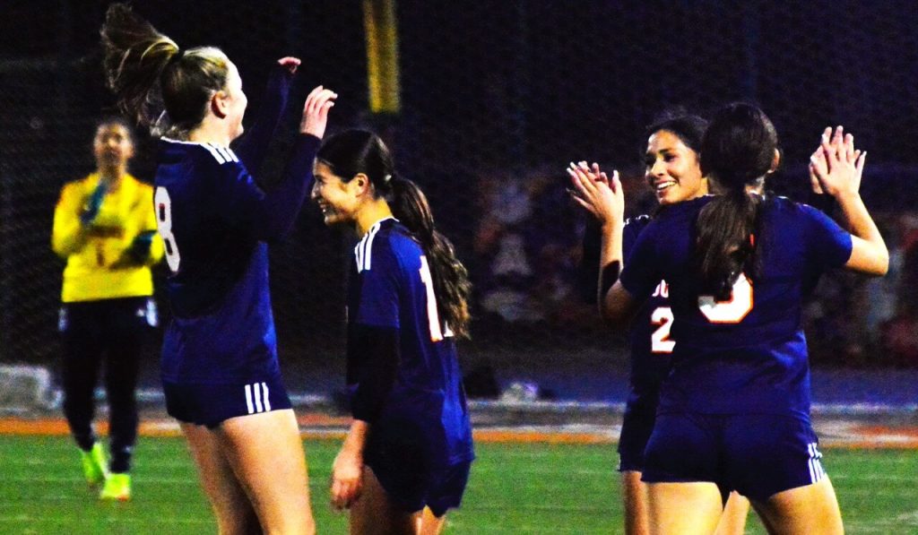Eastvale Roosevelt’s Gulianna Vargas (1), Presley Coles (8), Kayla Lawson (11), and Natalie Peregrina (5) congratulate Isabelle Salazar (22, facing camera) after Salazar’s long shot flew just under the crossbar and over the leaping Corona Centennial goalie. The Mustangs shutout the Huskies 5 – 0, and then two days later defeated Norco 2 – 1. Photo by Gary Evans