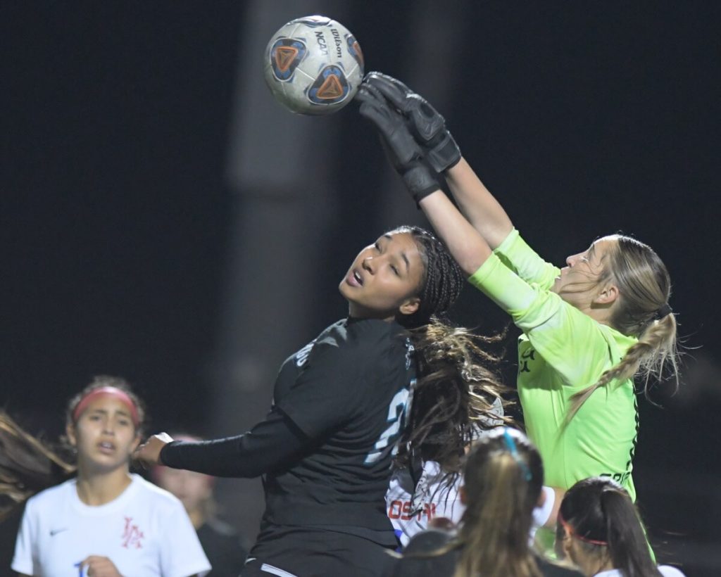 Championship Weekend. Los Alamitos goalie Avarie Gonzalez leaps to block an attempted header by Corona Santiago's Bri Norman in the second half of CIF open division semi-final game at Santiago. Santiago won, 1-0, to sweep the two-game series and earn a spot in the final vs Santa Margarita, this afternoon at 4:30 at Long Beach City College. Credit: Photo by Jerry Soifer