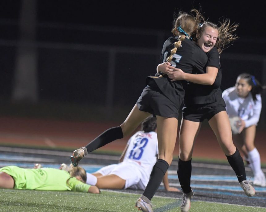 Corona Santiago's Maddy Saruwatari hugs teammate Alexis Coughlin after Saruwatari scored the game-winning goal late in the CIF Open Division semi-final at Santiago. The Sharks won, 1-0 to advance to this afternoon’s title game vs Santa Margarita. Los Alamitos goalie Avarie Gonzalez and defender Riley Zepeda lie on the field in despair. Credit: Photo by Jerry Soifer