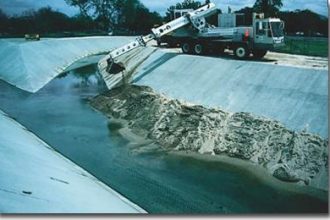 Sediment from undeveloped areas upstream flows through the high velocity portions of University Channel only to settle in areas where the velocity slows. Maintenance personnel remove material to maintain channel capacity.