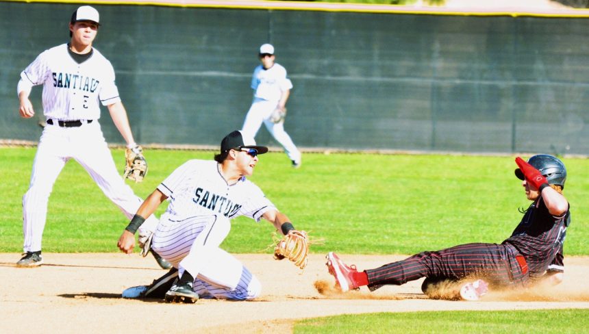 Corona Santiago shortstop Chris Ramirez (center) begins to slap down the inning-ending double-play tag on Centennial baserunner Aiden Simpson. Second baseman Austin Gamell watches the play. The Huskies defeated the Sharks 7 – 2. Credit: Photo by Gary Evans