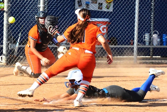 After retrieving a wild pitch, Roosevelt catcher Breanna Aguilar (left) flips the ball to pitcher Jazmine Chavez (11) but Norco’s Sasha Pham slides in safely at the plate. 
Credit: Photo by Gary Evans
