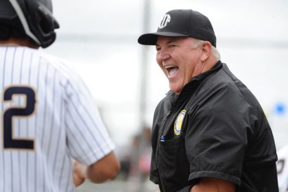 Caption: Retired Corona Police Lt. Brent Coleman is all smiles as he umpires the non-league baseball game between Fontana Kaiser and Riverside North in Riverside on Saturday. Kaiser defeated North, 4-3 Photo by Jerry Soifer