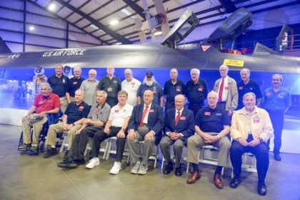 Pilots, reconnaissance specialist officers, and ground crew gather for a group photo by the SR-71 Blackbird at a mixer at the March Field Air Museum on Saturday. Credit: Photo by Jerry Soifer
