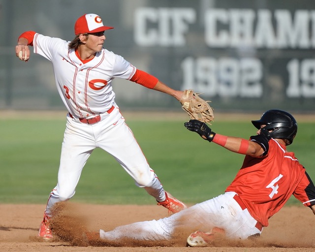 Featured Photos 4-19-2024 - Sports, Scoreboard - Corona shortstop Billy Carlson turns a double play over Corona Centennial's Ryder Dykstra as the Panthers remained undefeated in the Big VIII League with a 7-2 win on Monday. Credit: Photo by Jerry Soifer
