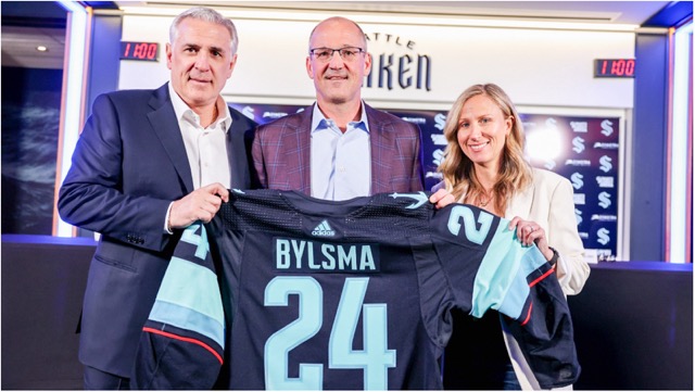 The newly named Seattle Kraken coach, Dan Bylsma, will continue to coach the Coachella Firebirds as they compete in the AHL Western Conference Championship for the second consecutive year. In a rapid round-trip to Seattle, he holds a Kraken sweater between team General Manager Ron Francis (l) and owner Samantha Holloway (r). Credit: Seattle Kraken