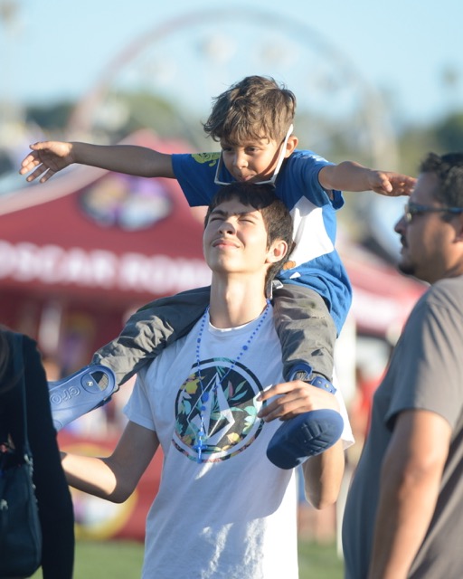 Caption: Eastvale resident Felix D'Allesandro, 18, carries his brother, Caeldus, 5, on his shoulders at the Eastvale Picnic in the Park Friday, the first day of the three-day event. More photos on page 7. Credit: Photo by Jerry Soifer