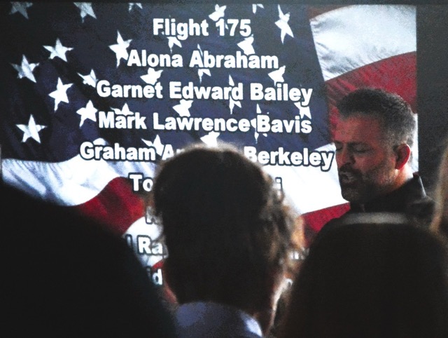 Grace Fellowship Church Pastor Phil Wozniak prays during the Norco 9/11 Remembrance Ceremony while the names of those lost multiple attacks on a big screen behind him. Photo by Gary Evans