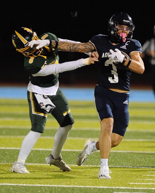 San Bernardino Aquinas JoJo Solis fends off a Riverside Notre Dame tackler on the opening kickoff at Ramona High School in Riverside. Aquinas won, 48-0.