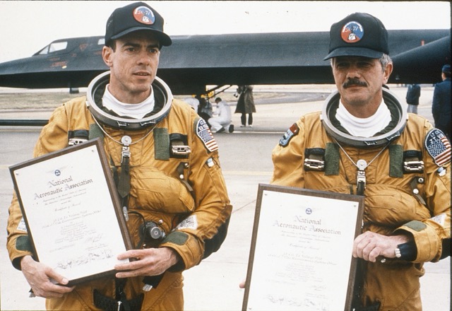 Record-setting pilot Ed Yeilding (l) and reconnaissance specialist. J.T. Vida (r) hold certificates commemorating their one-hour and seven-minute cross-country flight in an SR-71 Blackbird in 1990