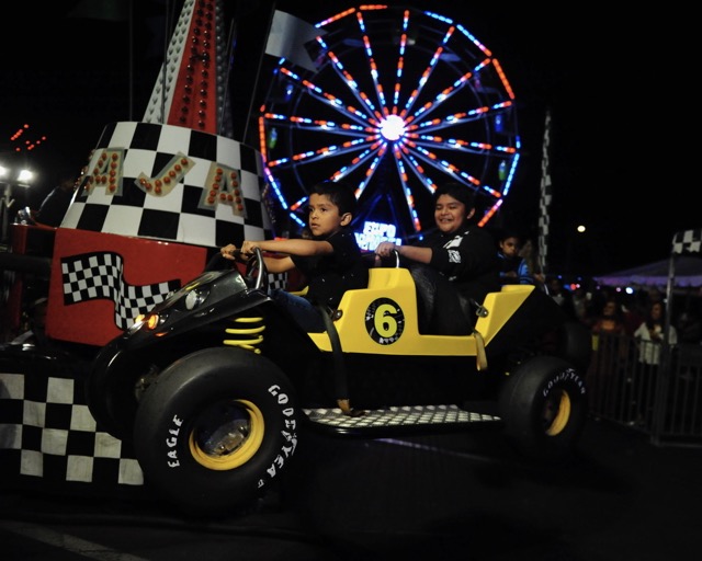 Young boys enjoy a dune buggy-themed spinning ride at Corona’s St. Edward Catholic Church Carnival last Saturday. Credit: Photo by Jerry Soifer