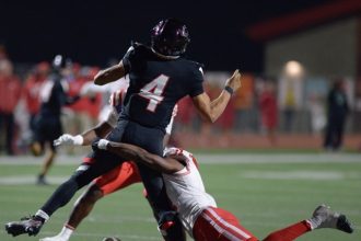 Corona Centennial quarterback Husan Longstreet who recently committed to USC loses the football under attack by Mater Dei defenders Friday in the CIF Div. 1 semifinal game at Centennial. Mater Dei won, 36-7.