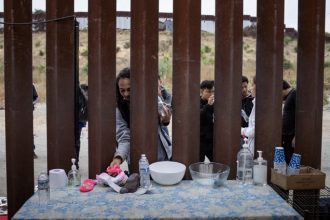 Presidential Race. Thauany Danielle, an asylum seeker from Brazil, grabs water and socks donated by the American Friends Service Committee as migrants wait to surrender to immigration officials after crossing into the U.S. from Mexico in San Diego on May 14, 2024. Photo by Adrees Latif, Reuters