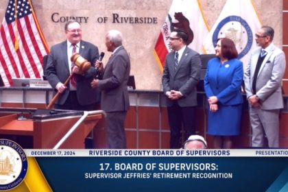 Supervisor Chuck Washington presents retiring Supervisor Kevin Jeffries with a three-foot gavel, recognizing his years of decorum and service. Supervisors Yxstian Gutierrez, Karen Spiegel and Manuel Perez (l-r) look on.