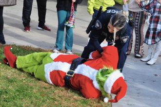 Corona police officer Maria Herrera a “Grinch” Santa at the Kids & Cops Holiday Magic event. Credit: Photo by Jerry Soifer