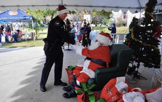 Corona Police Chief Robert Newman shakes hands with “Friendly” Santa, volunteer Oscar Figari. 
Credit: Photo by Jerry Soifer
