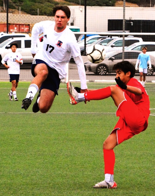 Eastvale Roosevelt’s Sebatian Halzuet (17) winces while avoiding the kick by a Redlands East Valley player during the Mustang’s 2 – 0 win over the Wildcats. Credit: Photo by Gary Evans