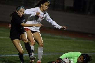 Corona high goalkeeper Brianna Cacao stops a scoring effort by Corona Santiago's Alyssa Fernandez who is defended by Corona's Alannah Noriega. Cacao was under pressure all night Thursday from Santiago in a 9-0 road loss in a Big Viii League game