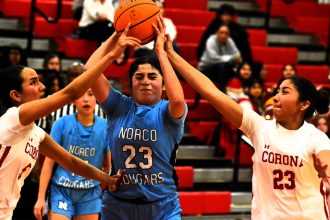 Corona’s Natalie Hernandez (left) and Alex Flores (right) converge on Norco’s Diana Castaneda (23) during the Panthers 54 – 15 win over the Cougars.