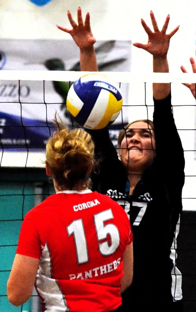 Corona’s Cora Jakubik (15) hits the ball into the net in front of Santiago’s Emerson Newton (37). 