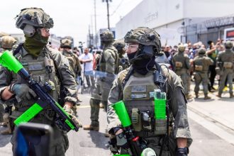 Federal Officers. Masked federal agents encounter protesters during an ICE raid at a garment company in Los Angeles on June 6, 2025. Credit:  Photo by J.W. Hendricks for CalMatters