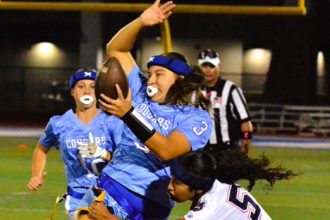 Norco High QB Mya Arriola (3) twists to avoid the flag pull of Eastvale Roosevelt’s Arianny Carretero (5).