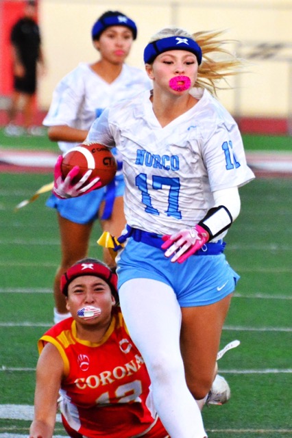 Corona’s Olivia Arroyo (lower left) dives and misses the flag of Norco’s Ryley Rocheleau during a punt return.  The Cougars extended their winning streak to 12, defeating the Panthers 30 – 6.