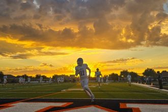 Friday Night Lights frames a stunning All-American tableau in Eastvale as Norco’s Riley Scheppmann (11) warms up before a gridiron clash of Cougars and Mustangs. Photos, Page 16. Credit: Photo by Gary Evans