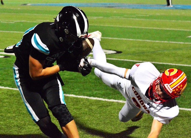 Featured Photos 10-31-2025. Santiago receiver Carter Ward (left) hangs on to the ball while Corona defender Jayden Goins (right) pulls Ward out of bounds. Credit: Photo by Gary Evans