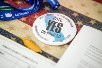 A button reads, “Vote Yes on Prop 50” at the Kings County Democrats booth during the Thursday Night Marketplace in downtown Hanford on Sept. 25, 2025. 