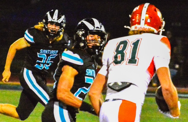Corona Santiago’s defenders Carter Tiedt (36) and Conner Skaggs (21) chase down Riverside Poly receiver Matt Henry (81) after a catch.